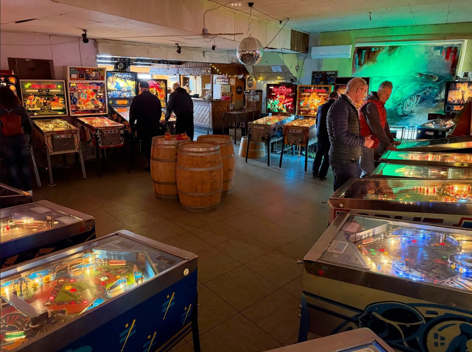 Kneipenbereich mit Theke, Fässern und Flippern im Flipperloft