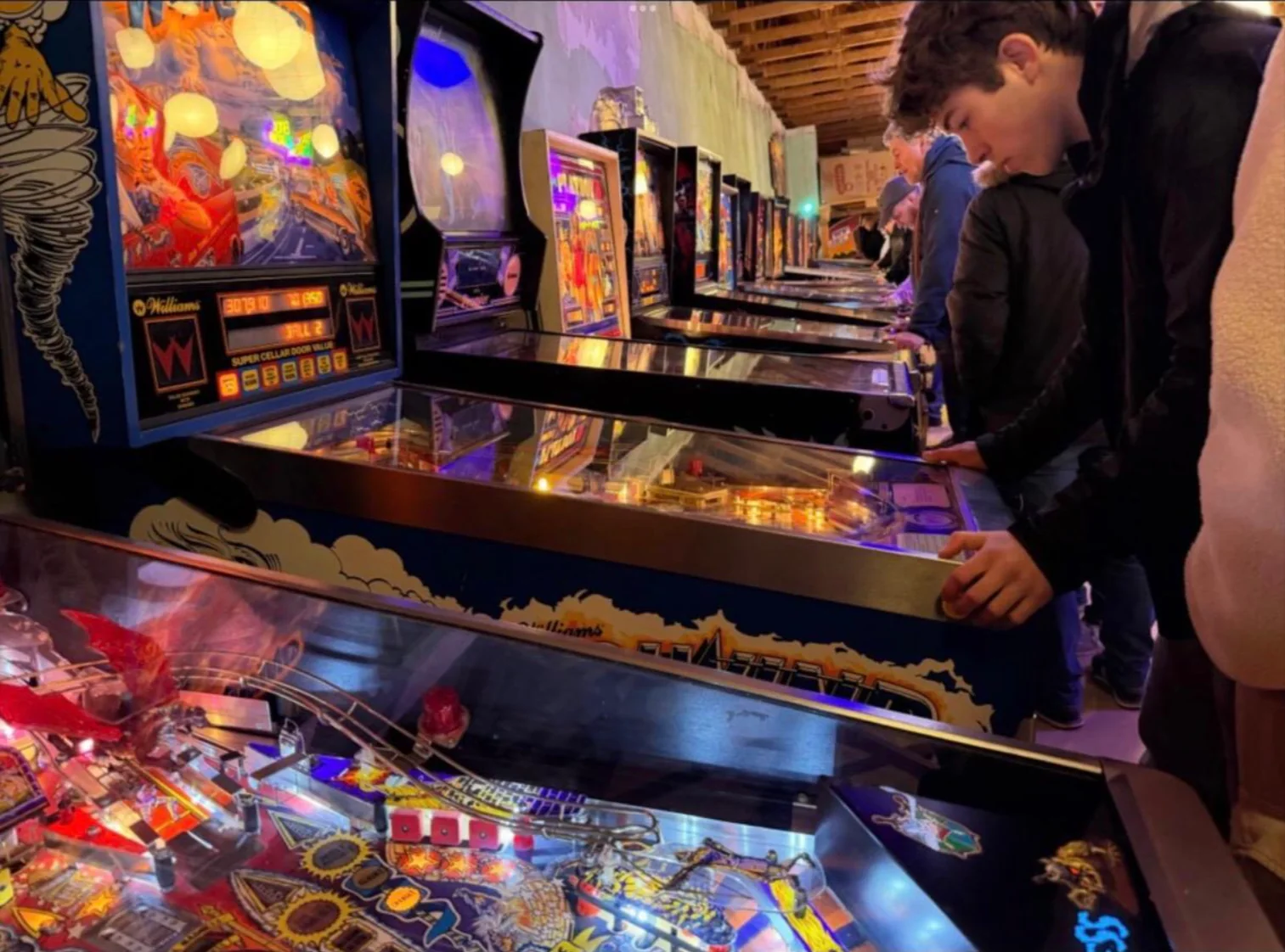 Mehrere Besucher spielen nebeneinander an Flippern im Showroom