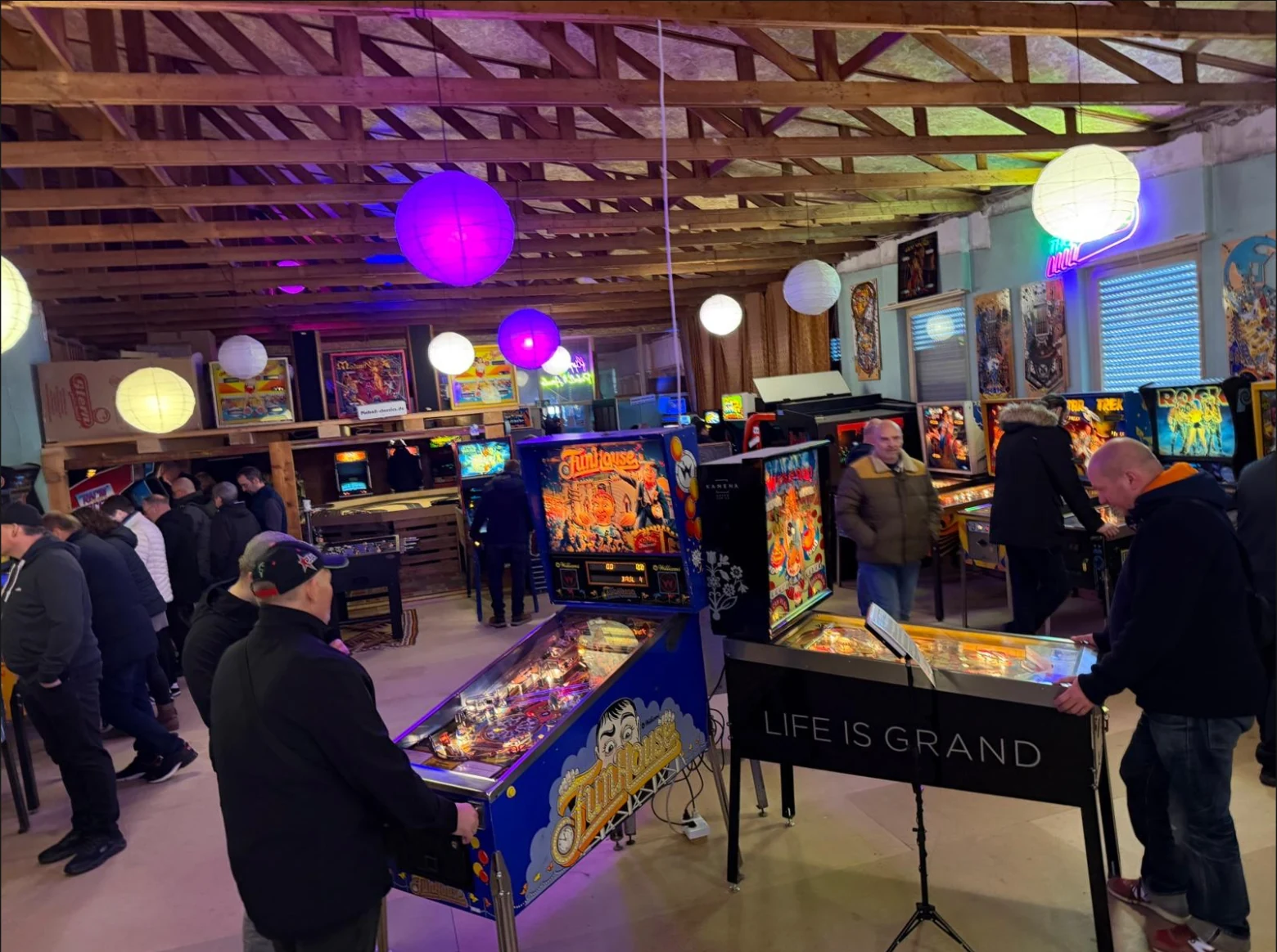 Gruppe spielt gemeinsam an einem Flipper im Flipperloft