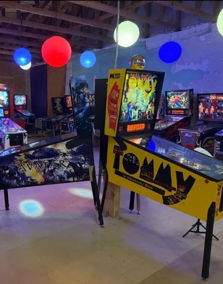Retro-Flipper-Ecke mit Wandgrafik und beleuchteten Maschinen